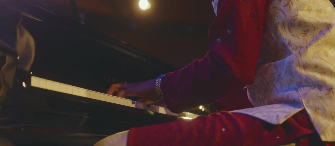 A black man plays piano in a concert hall