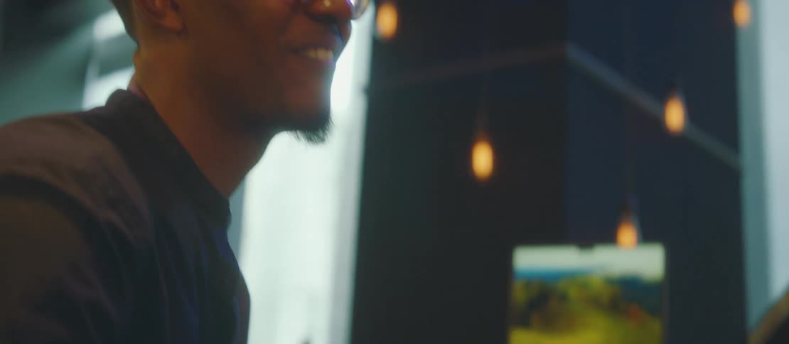 A black man smiles as he plays a piece on a piano