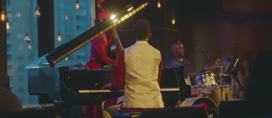 Musical group in a performance playing piano drums and guitar
