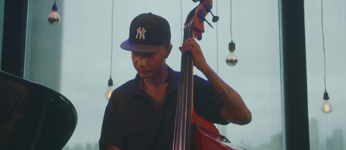A black man plays a large cello indoors