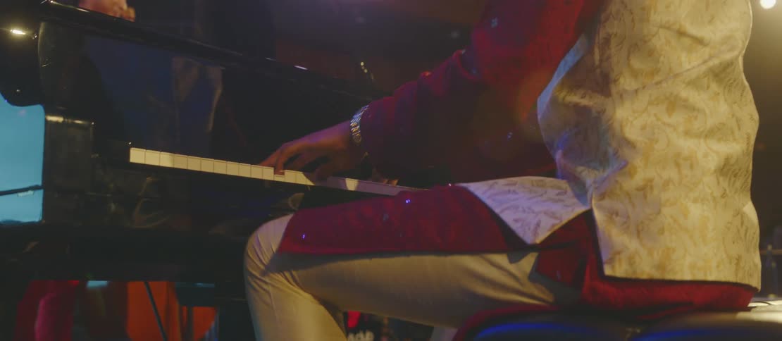Man sitting down tapping his feet and playing the piano in a performance