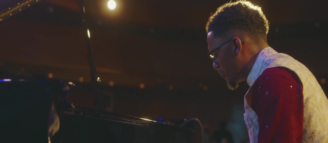 A black man plays piano in a concert hall
