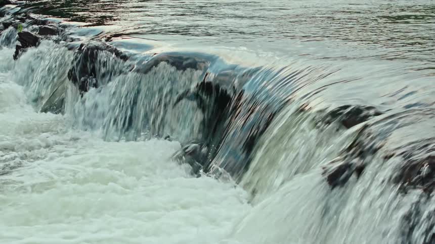 Small waterfall cascading over rocks into a frothy pool below