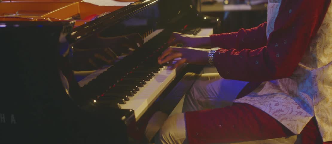 A man is playing the piano for a crowd