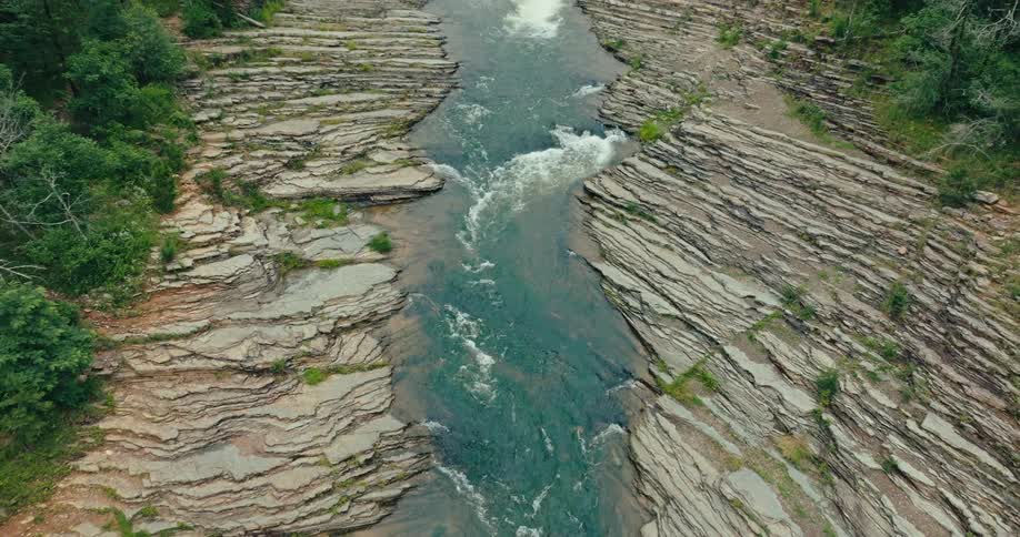A small river with rocks on the sides and a fast moving water