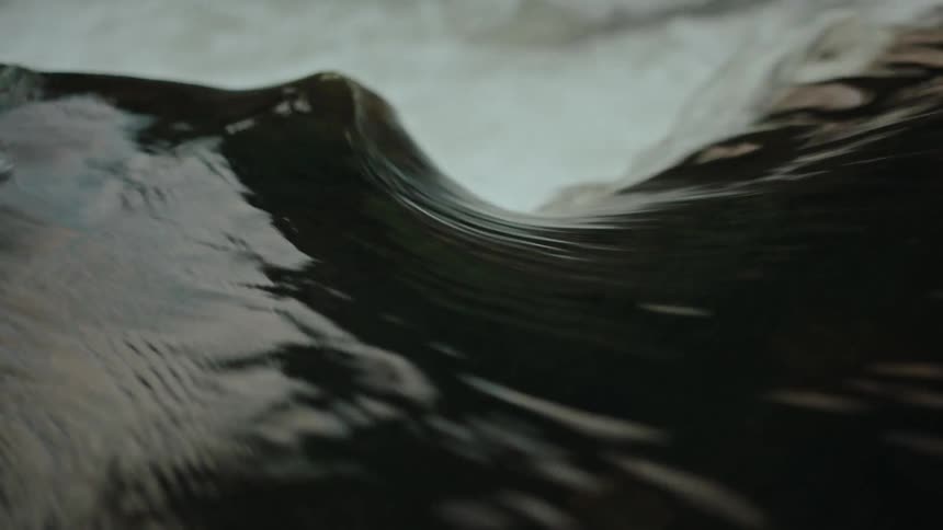 Dark reflective water flowing over a drop becomes churning whitewater