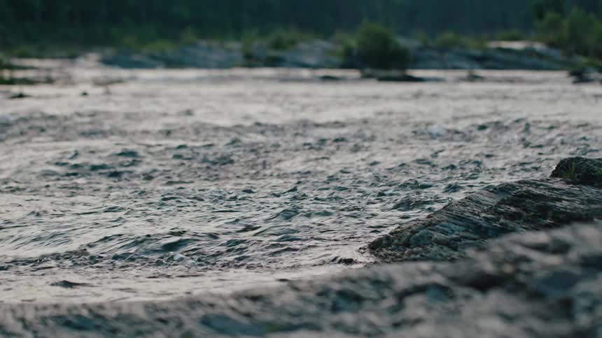 The blue water of a rushing river flows over rocky banks