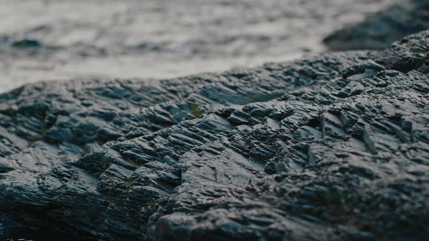 The waves crash on the rocks of the shore