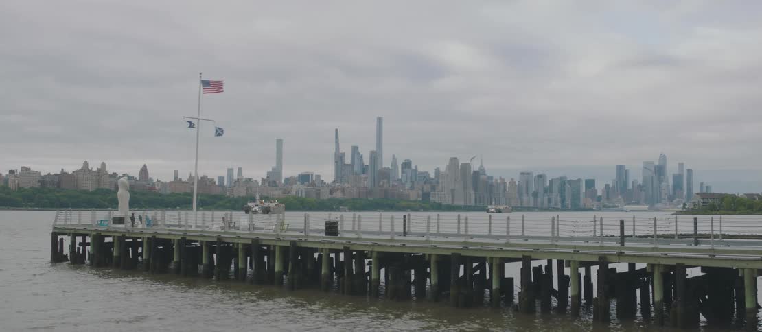 A bird flies over the empty pier by the city