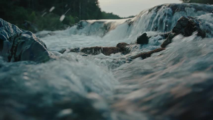 A stream with fast water passing between several rocks that are on the surface
