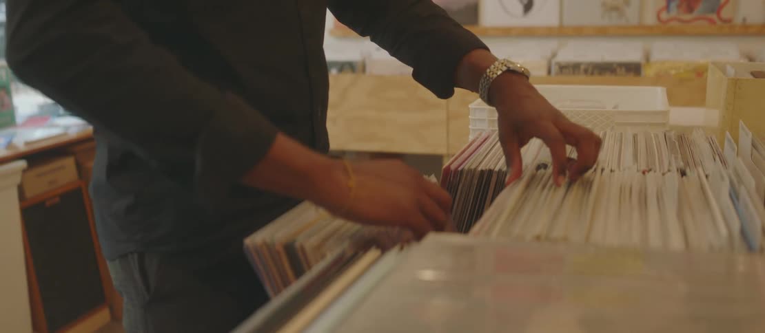 A young man going through a row of vinyl records at a record store