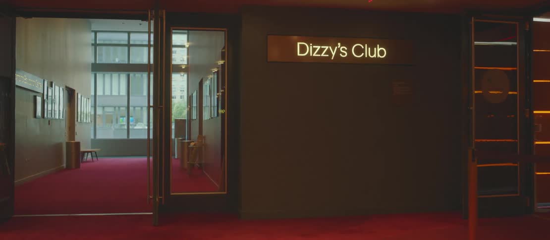 The interior of a club with a brown wall with some yellow lights separated by the environment and a glass door on the left side