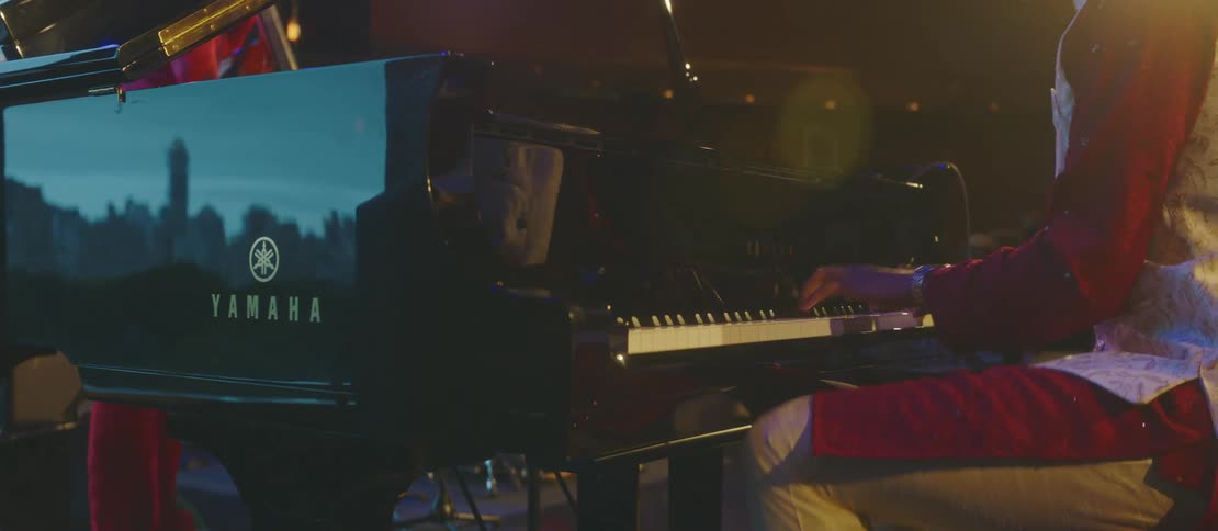A person sitting playing a black piano and shaking his leg up and down