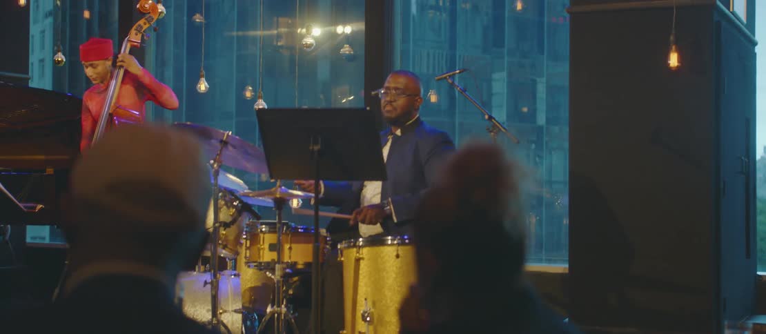 A trio of black musicians performs for a crowd in a building