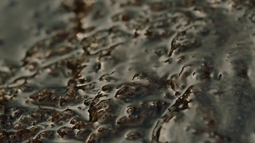 A surface of a stone that is being wetted by small waves of water