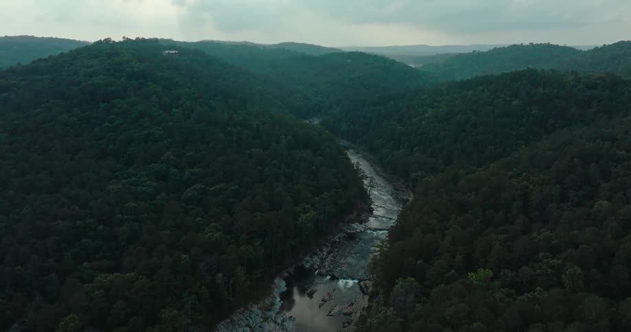 A river runs through the hills covered in trees