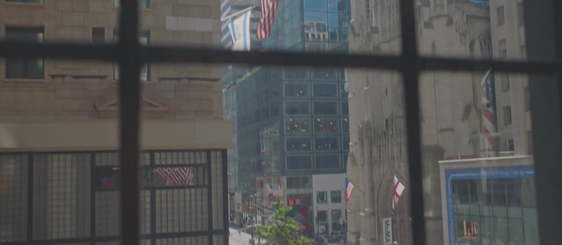 Tall city buildings give way to a busy street with heavy vehicle and pedestrian traffic