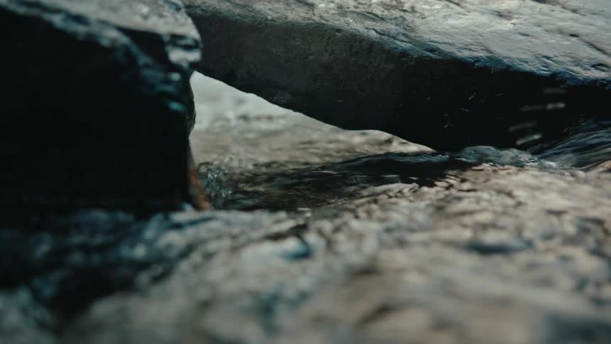 Closeup view of water flowing under rocks