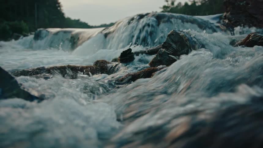 The water of a river passing rapidly between stones that are partially on the surface