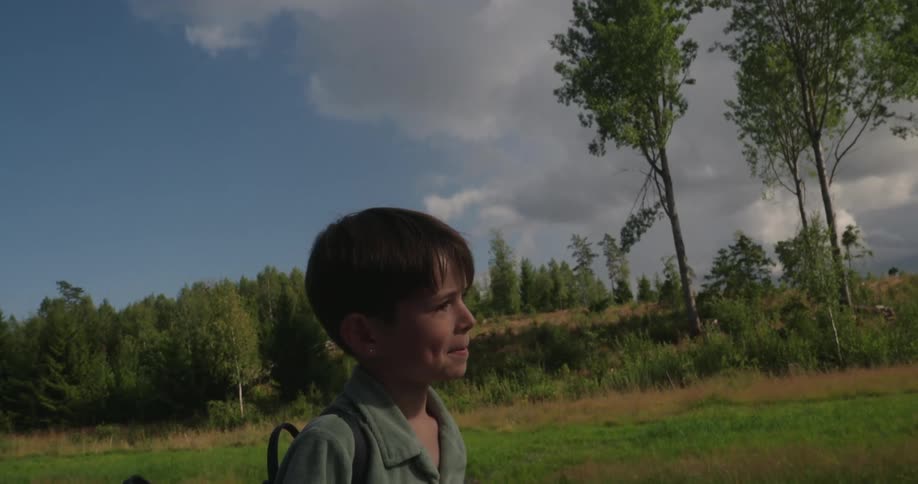 A clip of a boy walking along the grass field