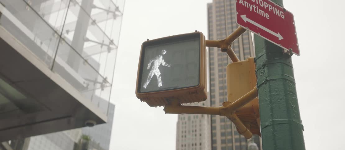 Pedestrian signal at a downtown intersection displays a walk symbol