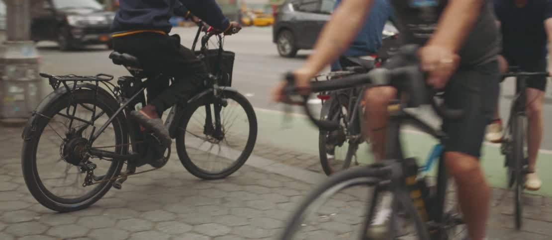 People riding bicycles next to an avenue with vehicle traffic
