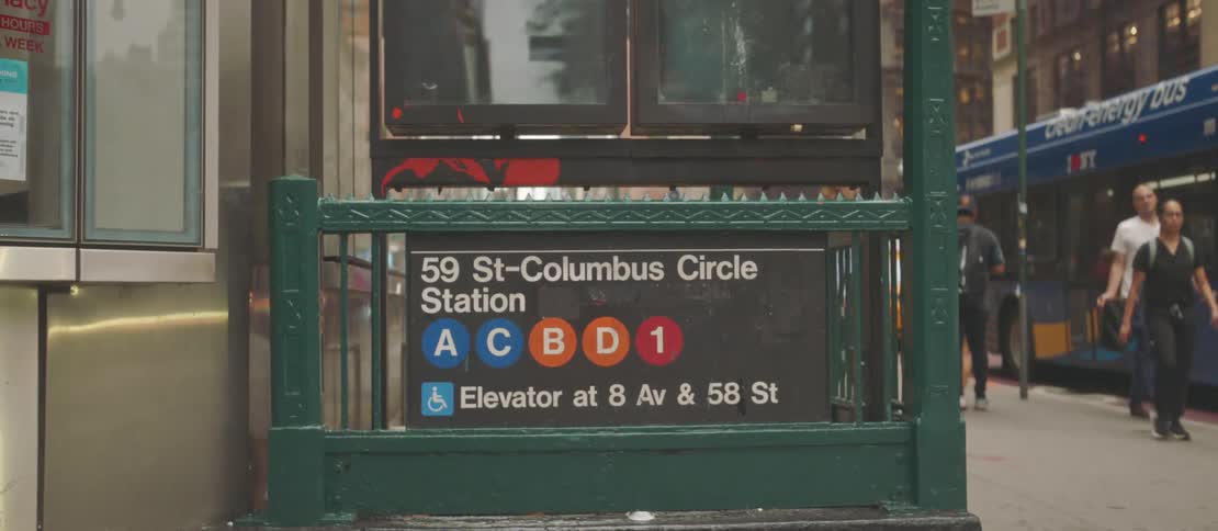 Sign of a subway station in a metropolis with people walking around