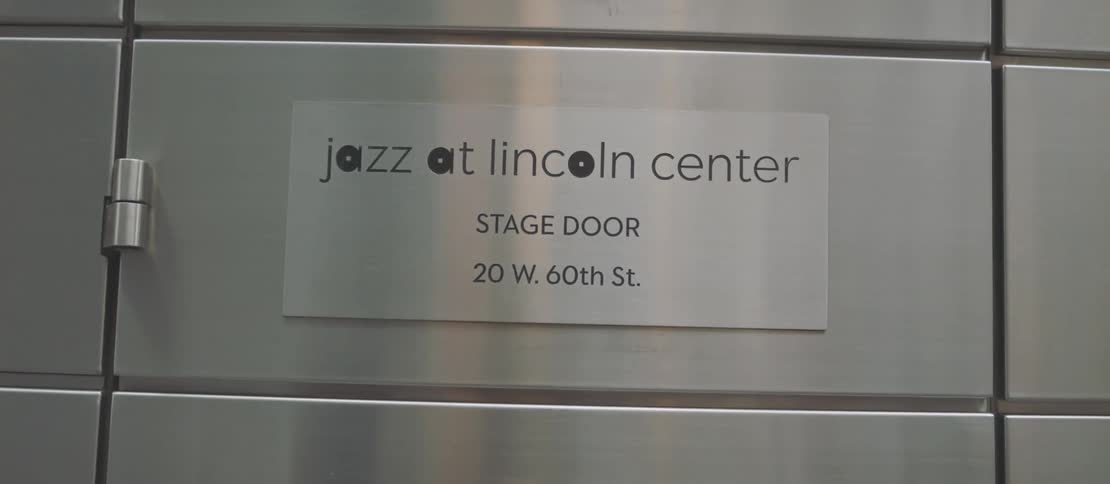 A gray metal plate with a text and is on a white tiled wall