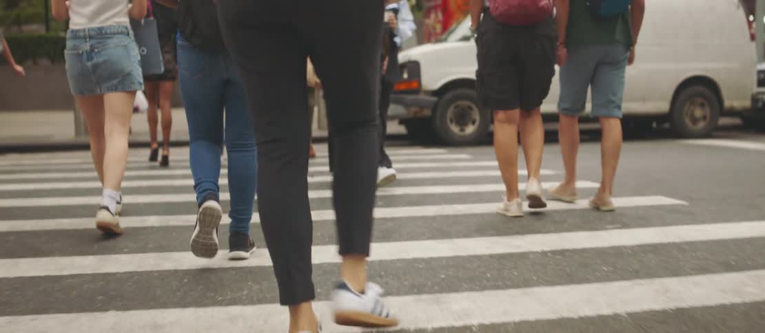 Legs of several people crossing the pedestrian crossing on a street in a busy metropolis