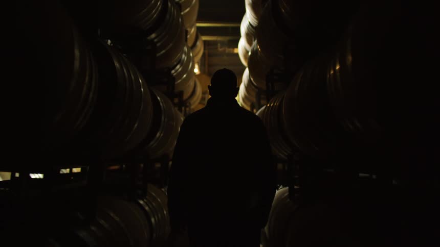 Man walks along an aisle between barrels in a warehouse