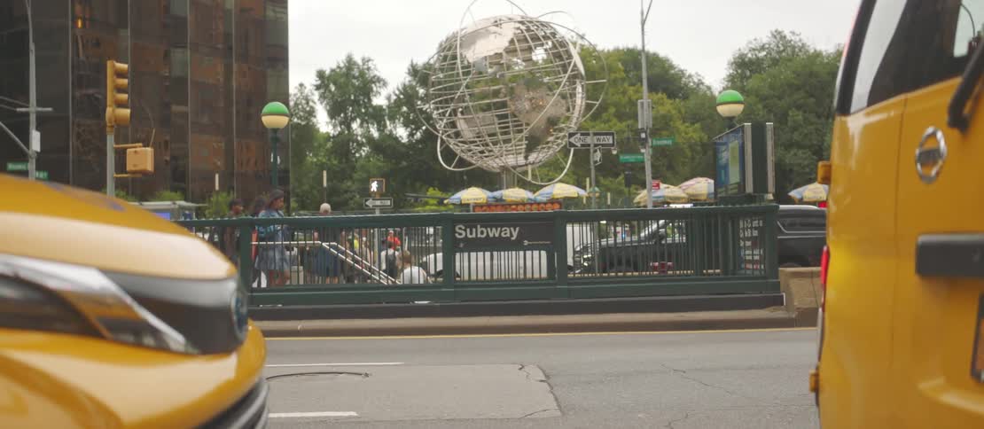 New york city street with a subway station yellow taxis and the iconic globe sculpture at columbus circle in the background