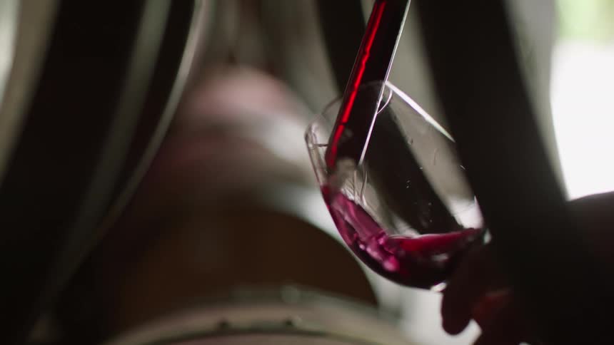 Wine from a barrel being poured into a glass goblet