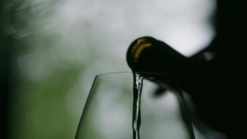 Bottle pouring white wine into a wine glass