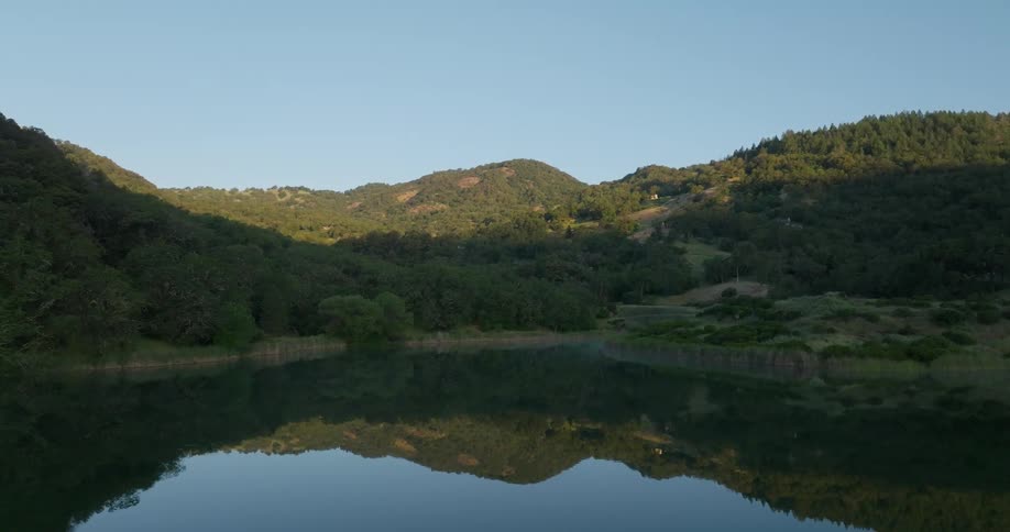 Aerial view of a lake reflecting the green mountains around it
