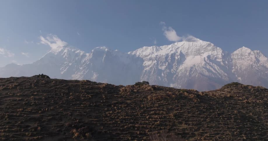 A huge mountain range with some of them covered in snow on their tops