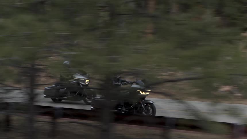 Two people ride motorcycles on the mountain road