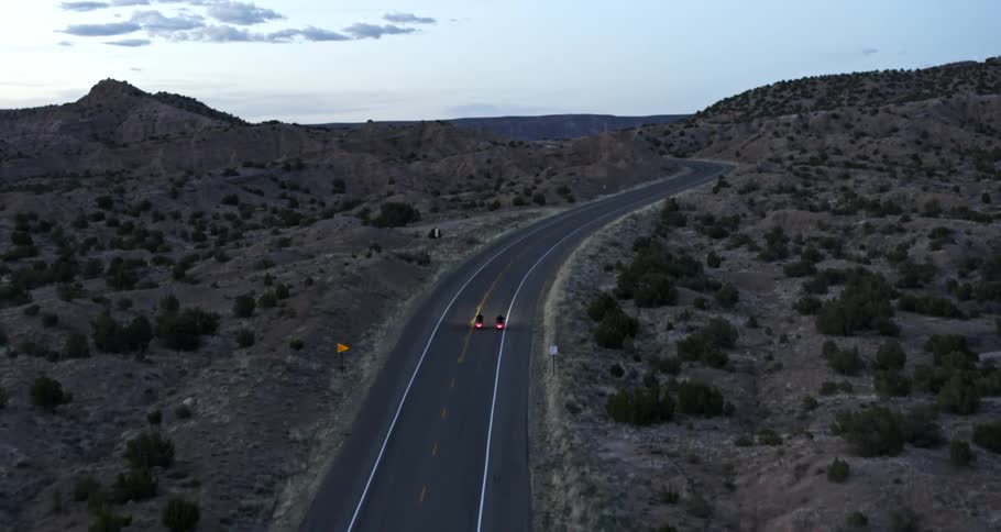 Aerial view of two motorcycles riding on a highway in the desert at dusk