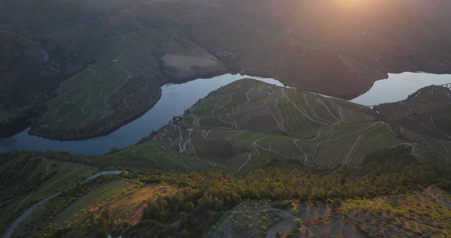 Aerial view of a river surrounded by mountain ranges and the suns reflection at dawn