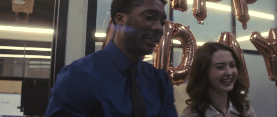 A man and woman laugh at a office birthday party