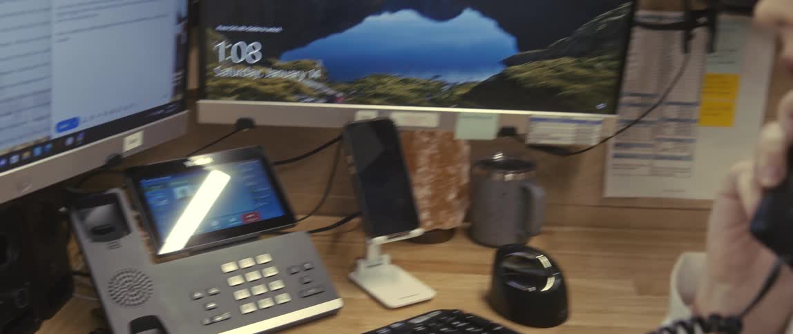 A young woman in an office cubicle sees the phone screen light up with a call and picks it up