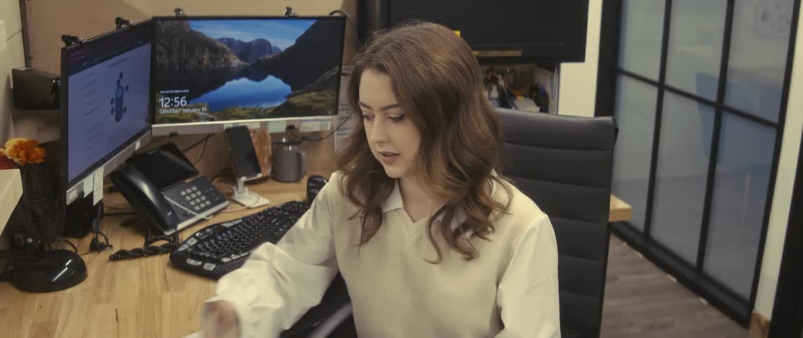A young woman receives some papers from a man in a suit in an office and she snorts afterwards