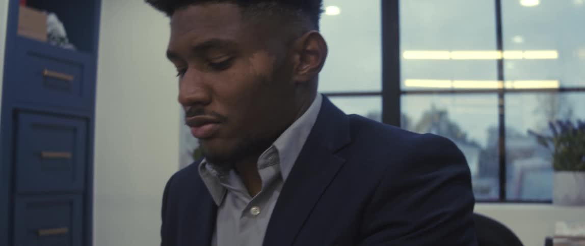 Businessman wearing a blazer jacket sits at a desk working in the office