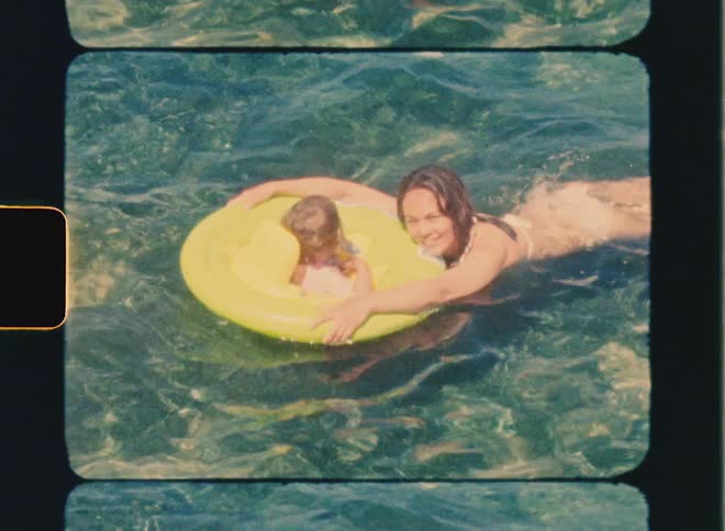 Super 8 film of a mother swimming with her baby in a buoy