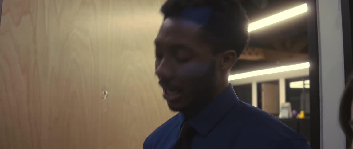 Two office workers smile and talk while standing in an office
