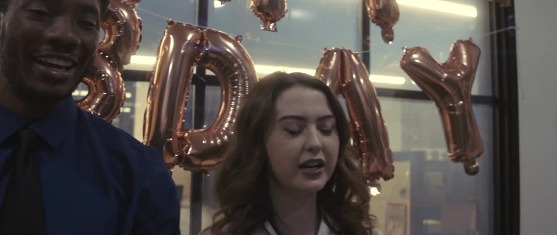 A male and female office employees smile and laugh in an office