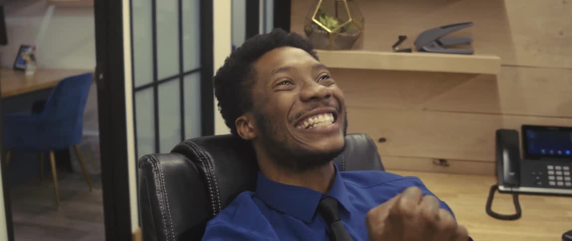 A happy office worker wearing a white shirt celebrates on his cubicle