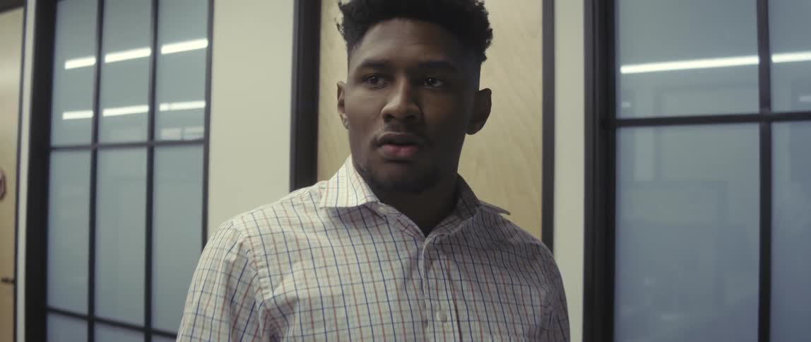 An employee handles forms near a copier before suddenly looking off into the distance