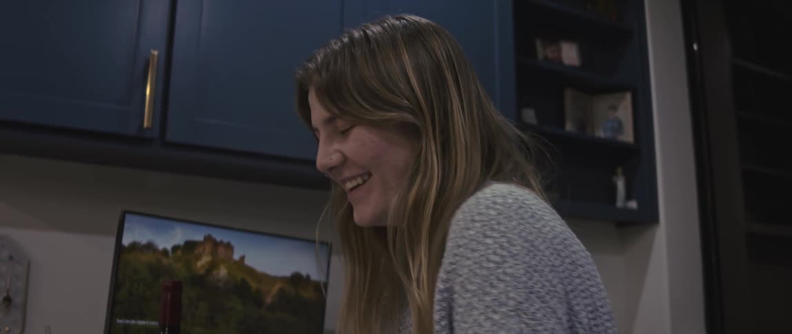 A young woman in an office talking and laughing shyly