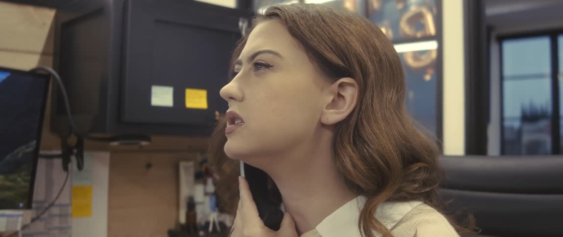 Portrait of a young woman sitting at an office desk talking on the phone