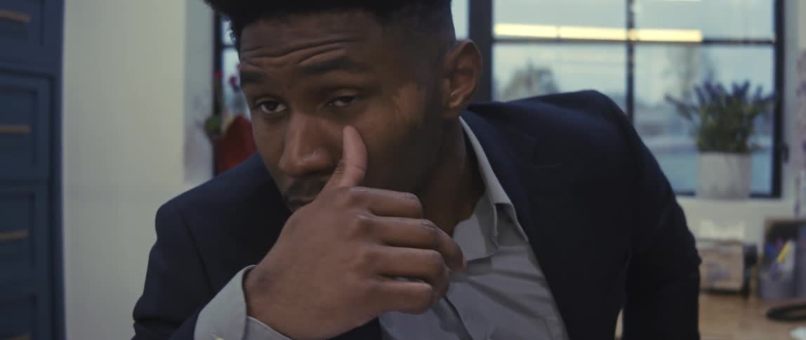 Stressed businessman wearing a navy blue jacket and gray shirt sits at desk at the office